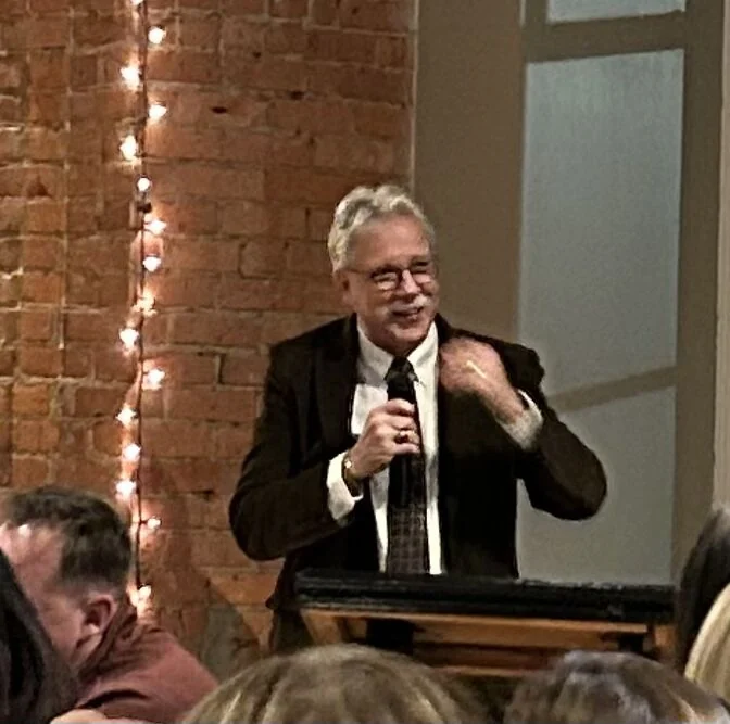 A speaker holds a microphone at a retirement celebration.