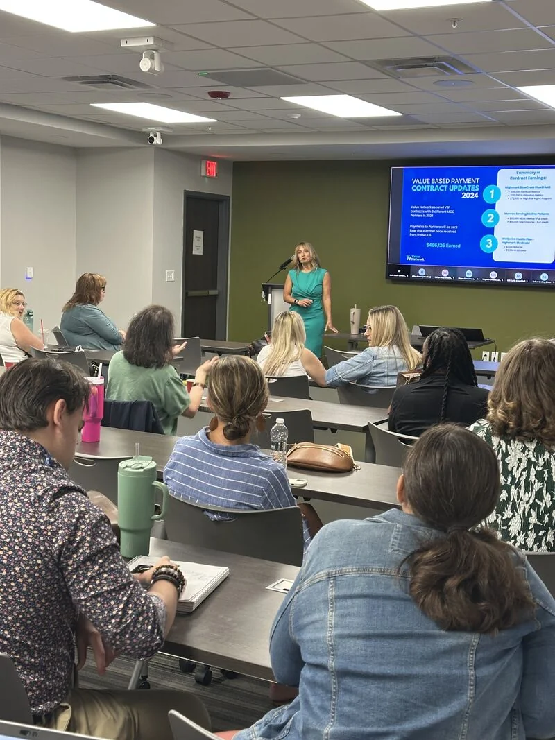 A presenter discusses value-based payment contracts with quarterly meeting attendees.